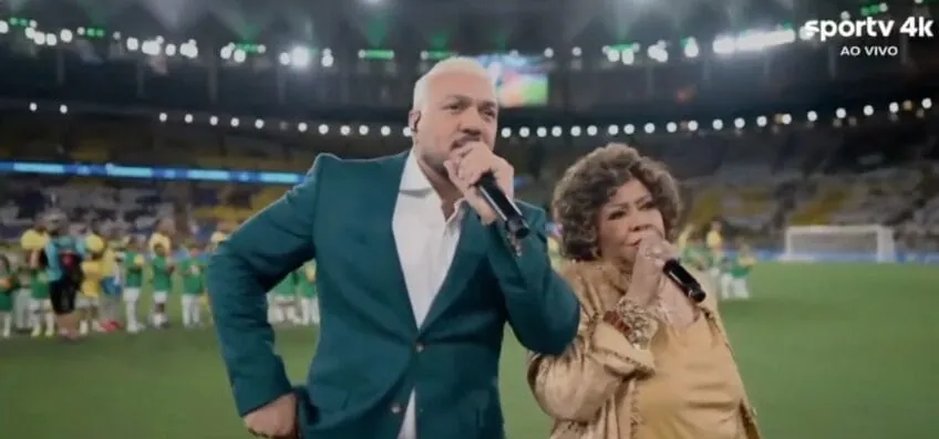 Belo e Alcione se atrapalham durante execução do Hino Nacional